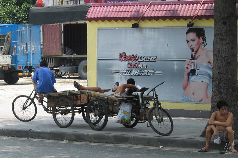 0506gz_IMG_1706.jpg - Le contraste entre les belles pubs modernes de boissons rafraîchissantes et les transporteurs à vélos, se reposant du climat subtropical humide de Guangzhou (38°C et 98% d'humidité en juillet)...croyez moi, pour nous c'est invivable!